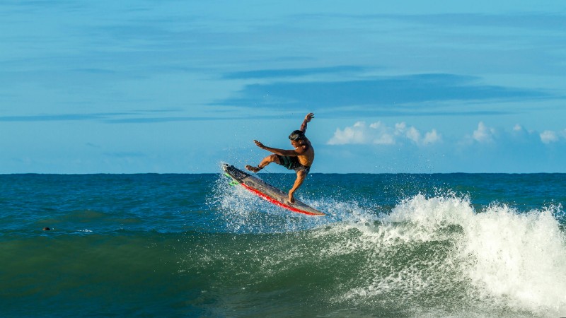 Surfer performing an aerial maneuver on a sunny day, showcasing dynamic surfing skills., tags: und - pexel