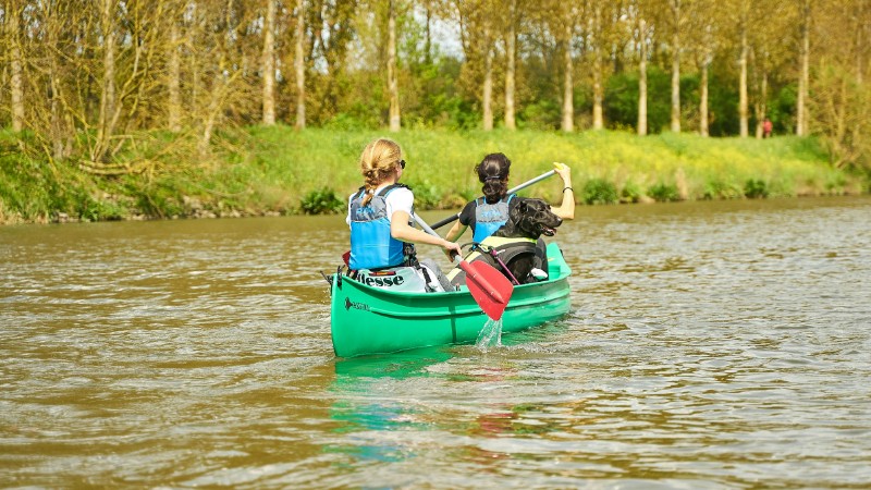 Two women paddle a green canoe on a calm river, enjoying a sunny summer day., tags: donau - pexel