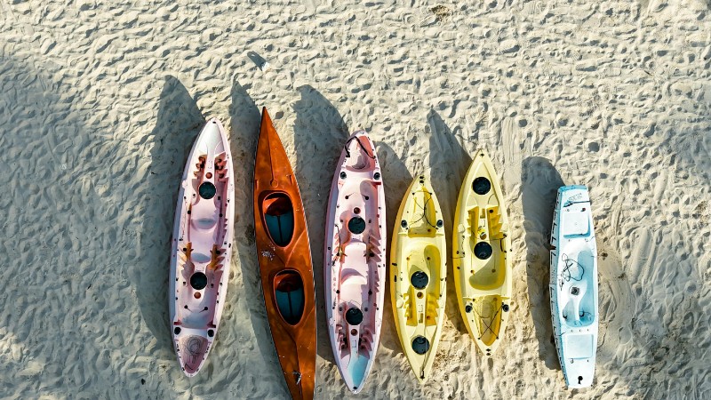 Aerial view of vibrant kayaks resting on sunlit sandy beach, perfect for outdoor adventure imagery., tags: gegen den strom: - pexel